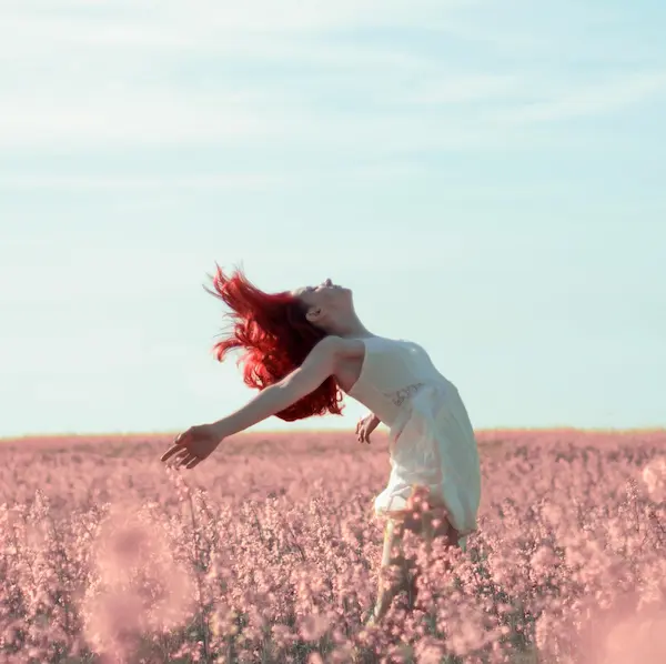 Mujer mirando al cielo con los brazos abiertos
